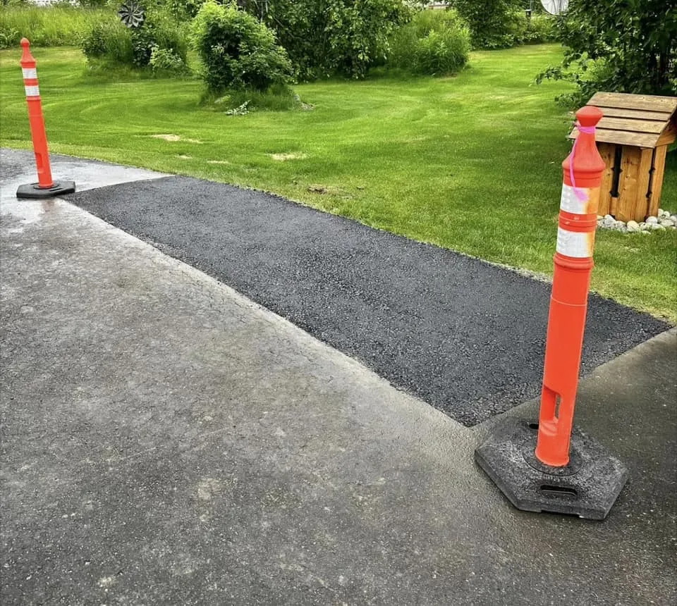 Fresh asphalt repair patch bordered by traffic cones