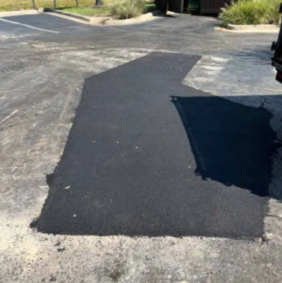 Dark rectangular asphalt patch on an older paved surface