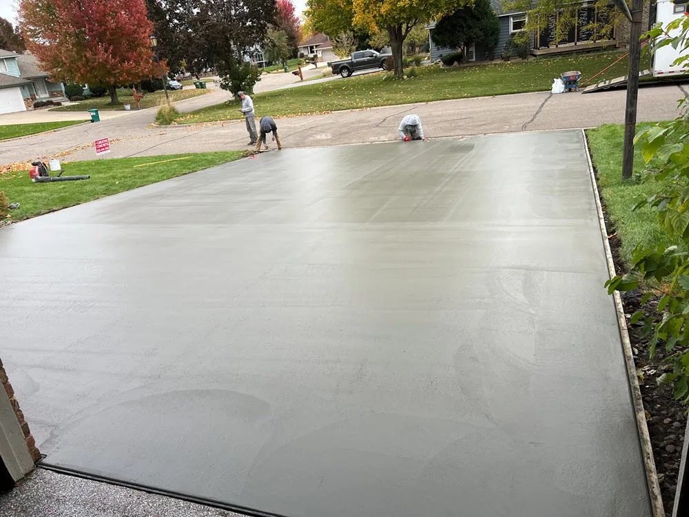 Newly poured concrete driveway with crews working along the far edge