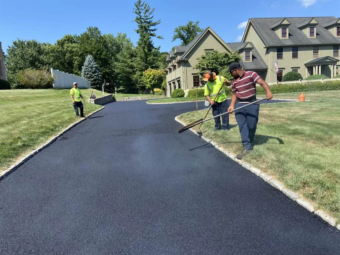 Workers finishing a freshly paved residential driveway